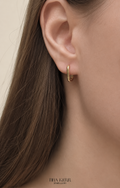 Gold hoop earring worn by a person with a neutral background