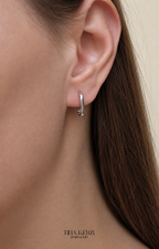 Silver hoop earring worn by a person with a neutral background