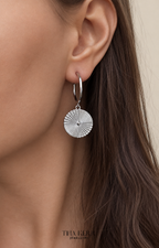 Close-up of a silver hoop earring worn by a person with long brown hair.