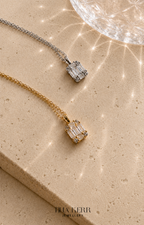 Two diamond pendants on a beige surface with 'Tina Kerr Jewellery' branding.
