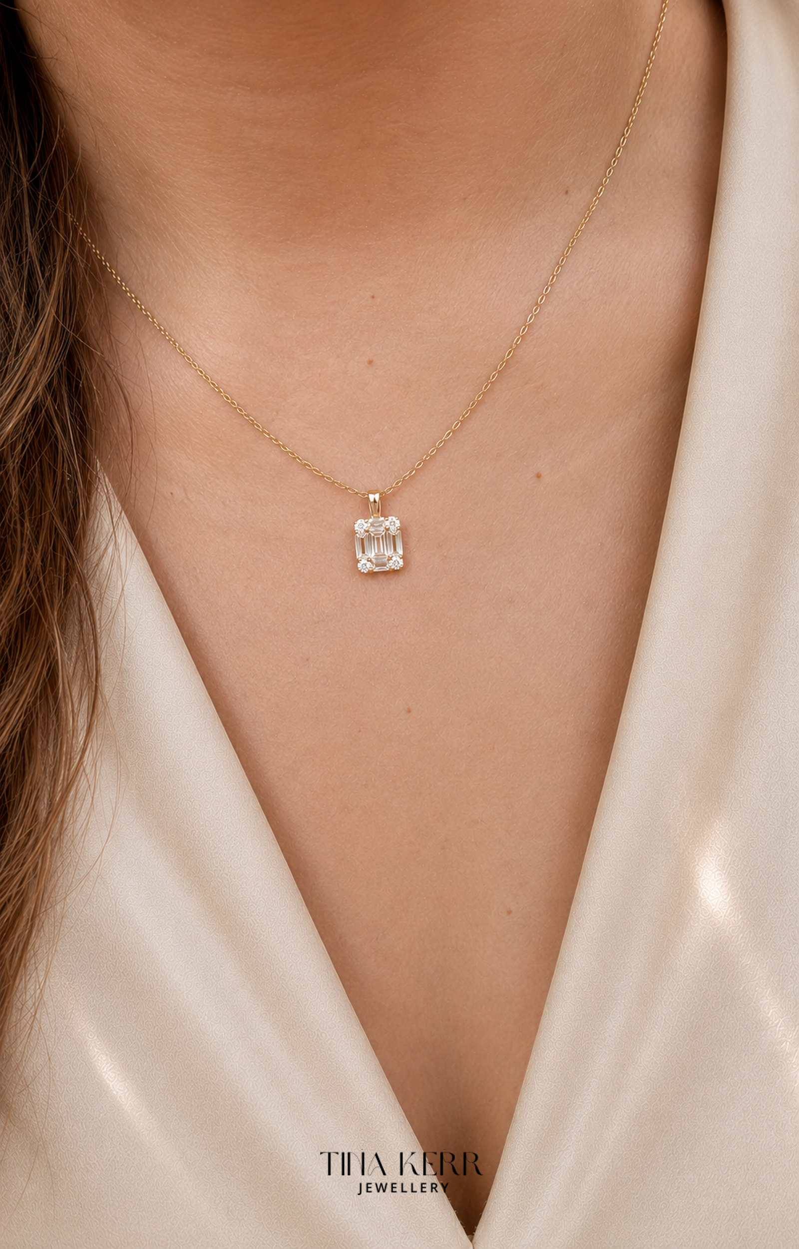 Gold necklace with a diamond pendant worn by a person in a white garment, branded 'Tina Kerr Jewellery'.
